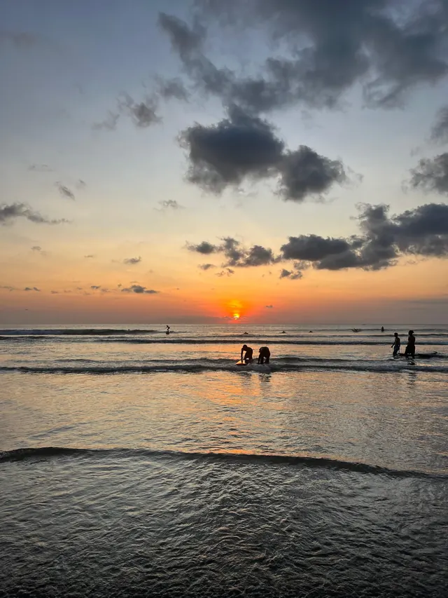 Surfers in the water at sunset in Bali