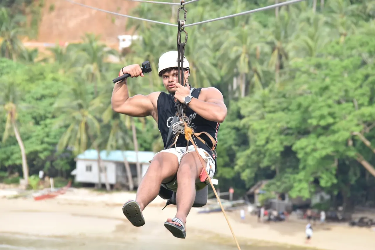 Dainyel ziplining above a tropical beach
