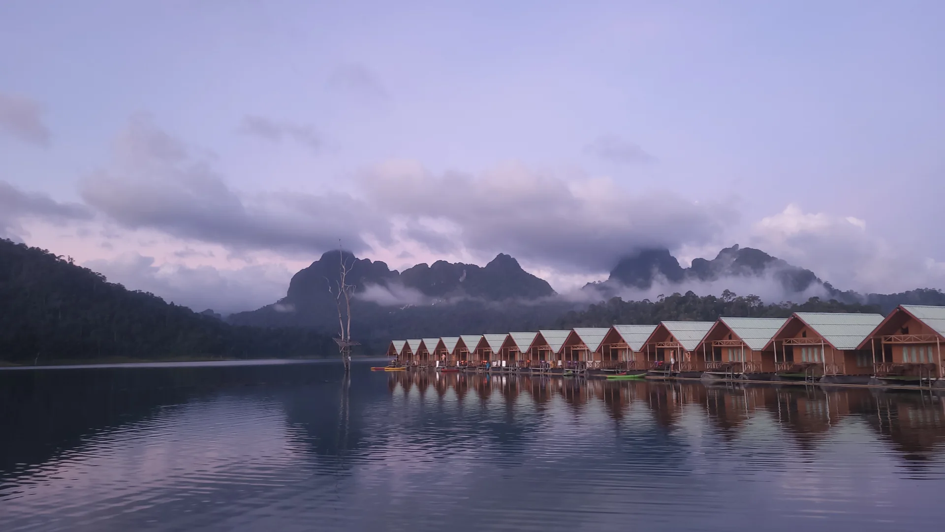Floating lodges on a still lake beneath misty mountains in Khao Sok